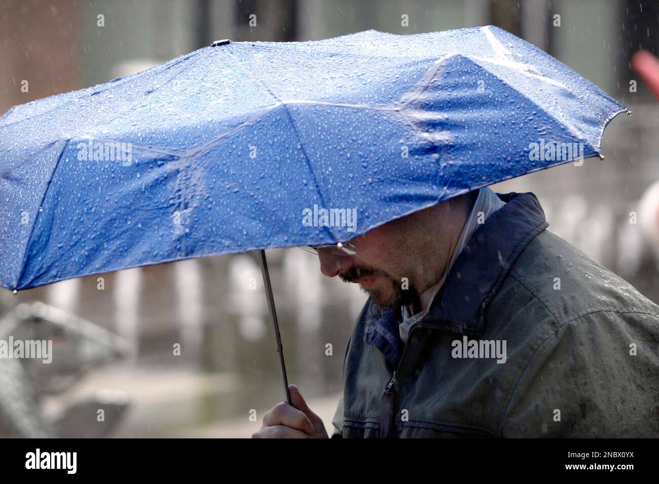A man shelters himself from rain showers under an umbrella as he walks through downtown Pittsburgh, Tuesday, May 3, 2011. The National Weather Service forecasts a chance of rain in the Pittsburgh area every day but Thursday for the next five days. (AP Photo/Keith Srakocic) Stockfoto