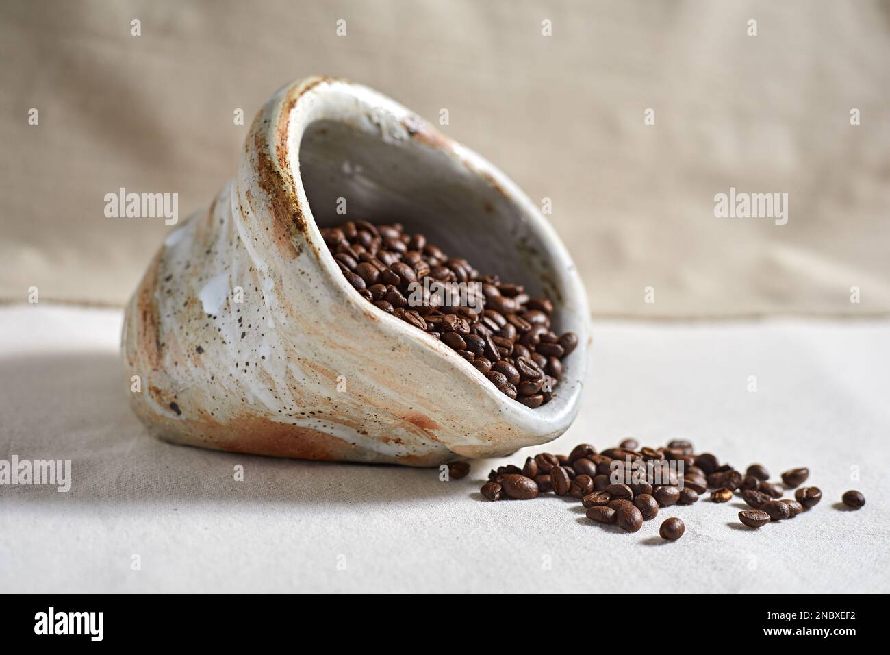 Verschüttete Kaffeebohnen aus Keramik auf Textil background.selective FOCUS Stockfoto