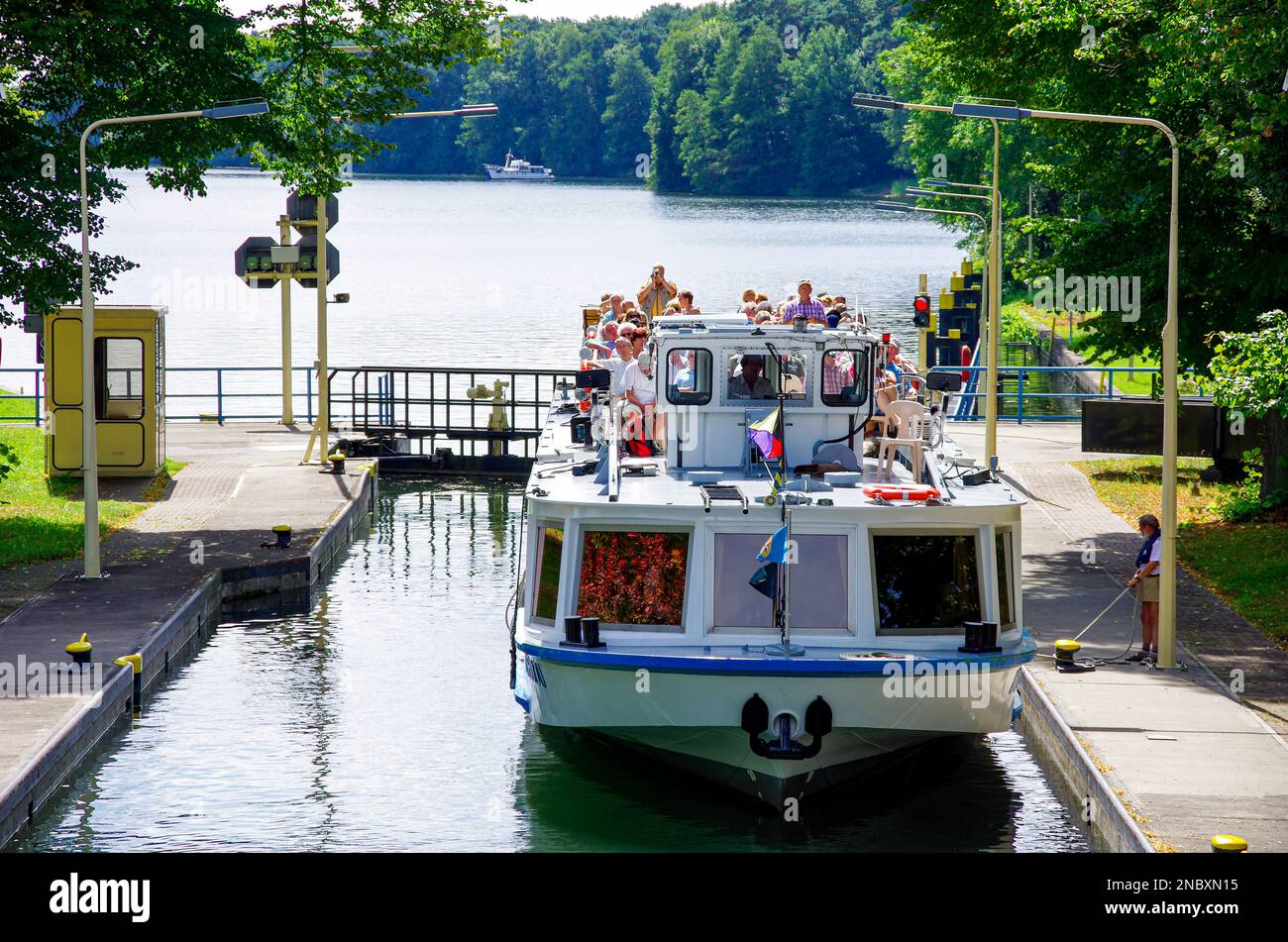 Ein Touristenboot voller Tagesausflügler wird durch die Woltersdorf-Schleuse geleitet, die aus Flakensee, Woltersdorf, Brandenburg, Deutschland kommt. Stockfoto
