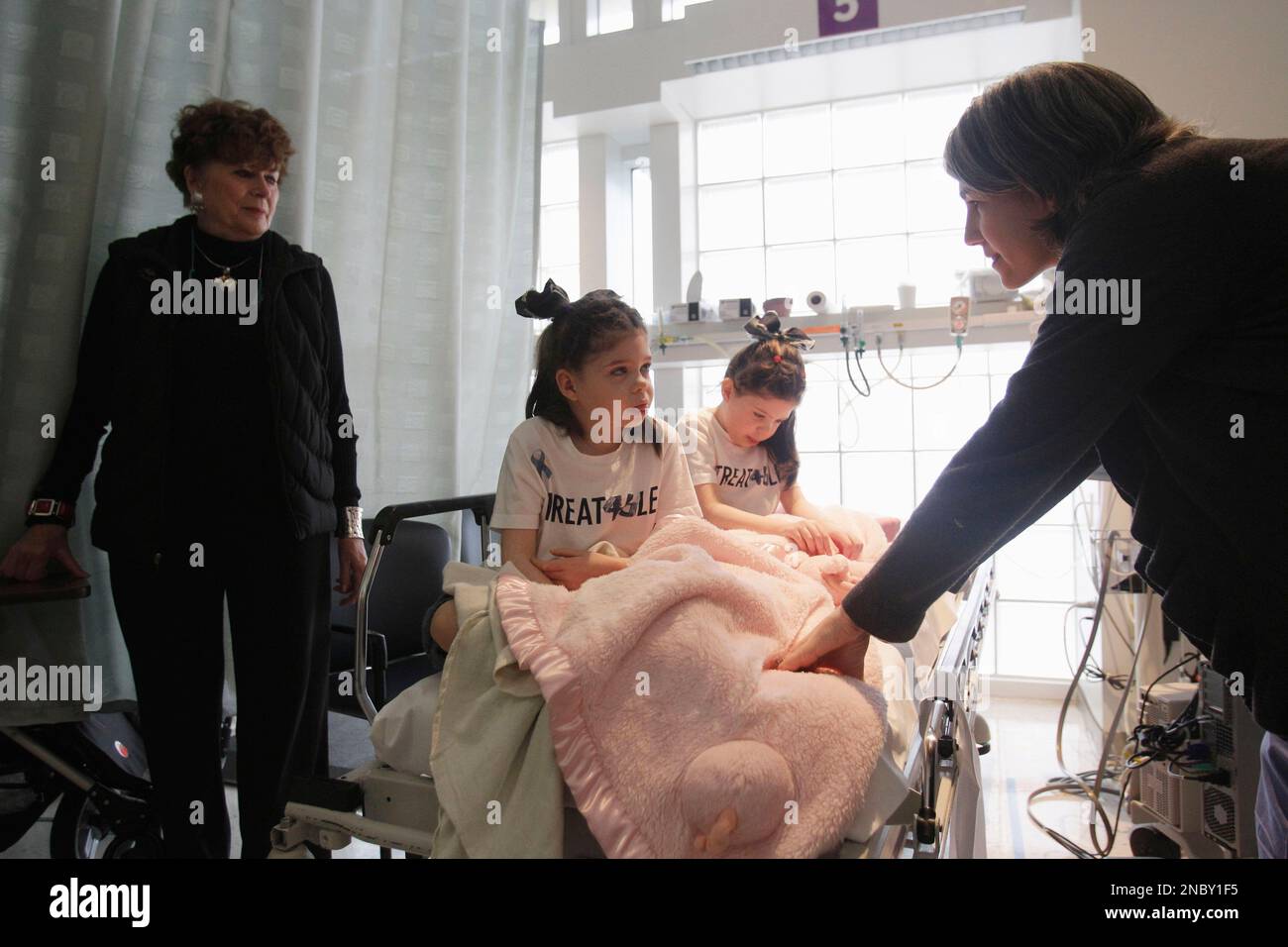 Chris Hempel, at right, comforts her twin daughters Cassidy, 6, center