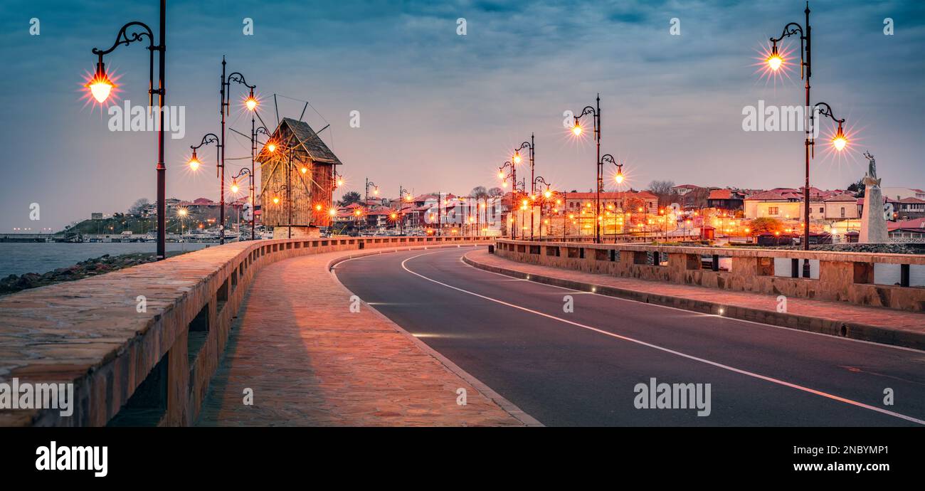Abendlicher Panoramablick auf die Altstadt von Nessebar mit Holzwindmühle. Beleuchtete Frühlingsszene von Bulgarien, Europa. Hintergrund des Reisekonzepts. Stockfoto