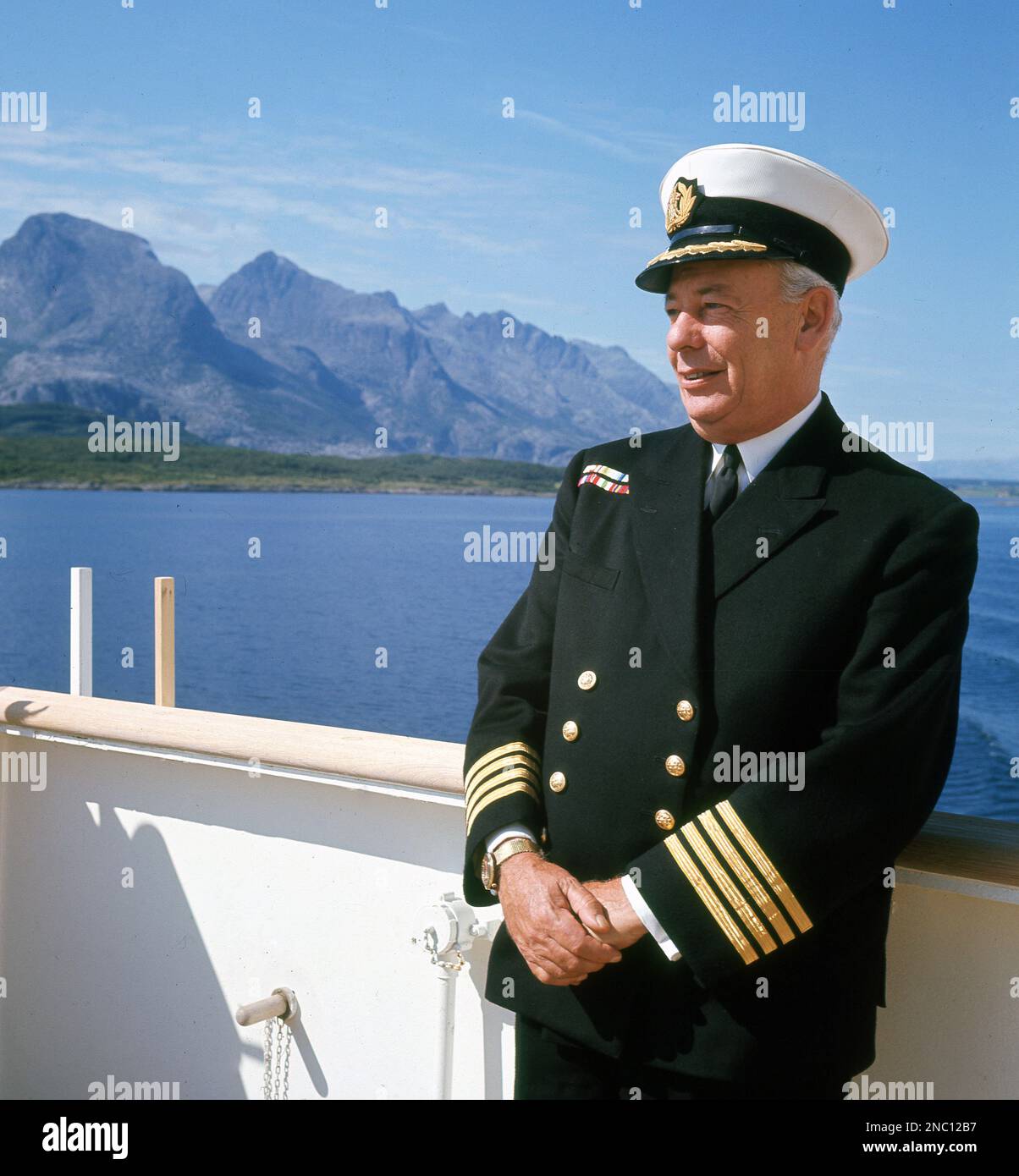 1960er Uhr, historisch, Porträt des Kapitäns (oder Meisters) des SS Uganda Dampfschiffs draußen auf dem Deck in voller Uniform. Sie wurde 1952 für die British-India Steam Navigation Company als Passagier- und Frachtschiff erbaut und segelte zwischen London und Ostafrika. Der Anstieg in der Zivilluftfahrt verzeichnete einen Rückgang der Nachfrage und so wurde sie Ende der 1960er Jahre zu einem Kreuzfahrtschiff mit Ausbildung umgewandelt, als ihre Frachträume in Schlafkabinen umgewandelt wurden. Sie segelte dann in Skandinavien und im Mittelmeer bis 1982, als sie von der Royal Navy als Krankenhausschiff im Falklandenkrieg benutzt wurde. Stockfoto