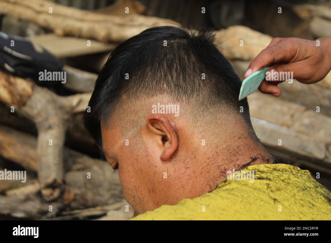 Meister schneidet im Friseursalon Haare und Bart von Männern, Friseur macht Frisuren für einen jungen Mann im Hintergrund von Fleck Stockfoto