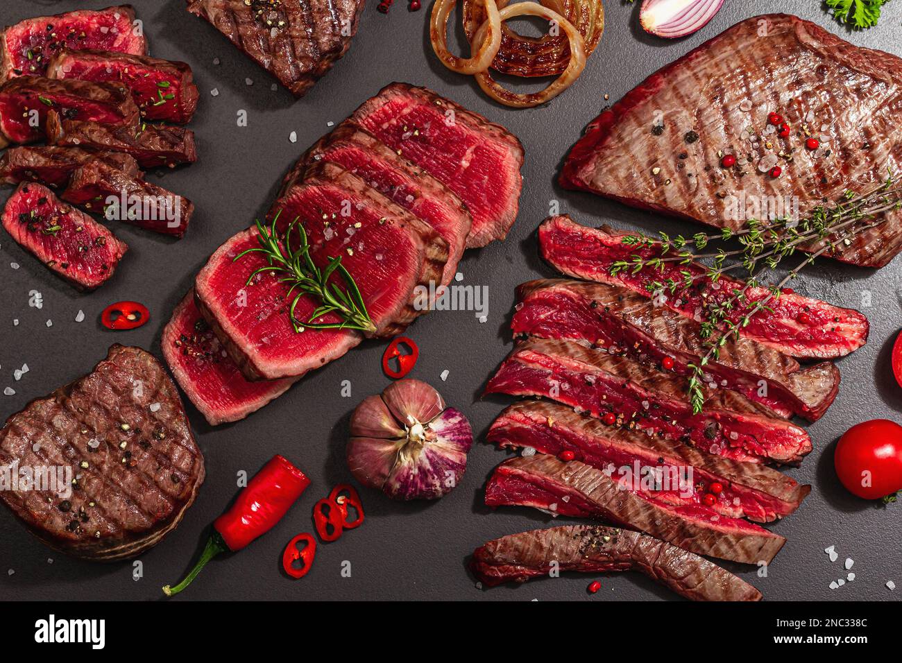 Gegrilltes Set mit verschiedenen Steaks mit Gemüse, Gewürzen und ...
