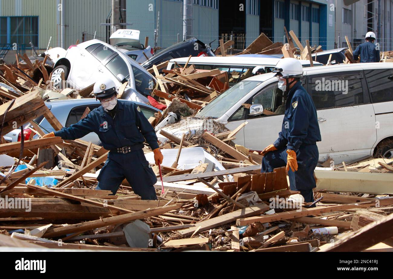 Rescue workers sift through debris at Sendai airport in Sendai, Miyagi Prefecture, Japan, Saturday, March 19, 2011. The U.S. military have been asked to help clear the debris from last week's earthquake-triggered tsunami to get the airport fully operational as soon as possible. (AP Photo/Mark Baker) Stockfoto