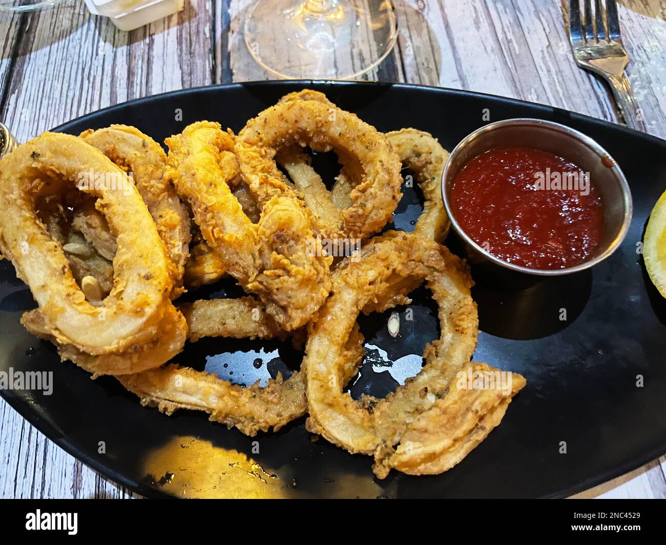Ein Teller frittierter Calamari mit Meeresfrüchtesauce und Zitrone. Stockfoto