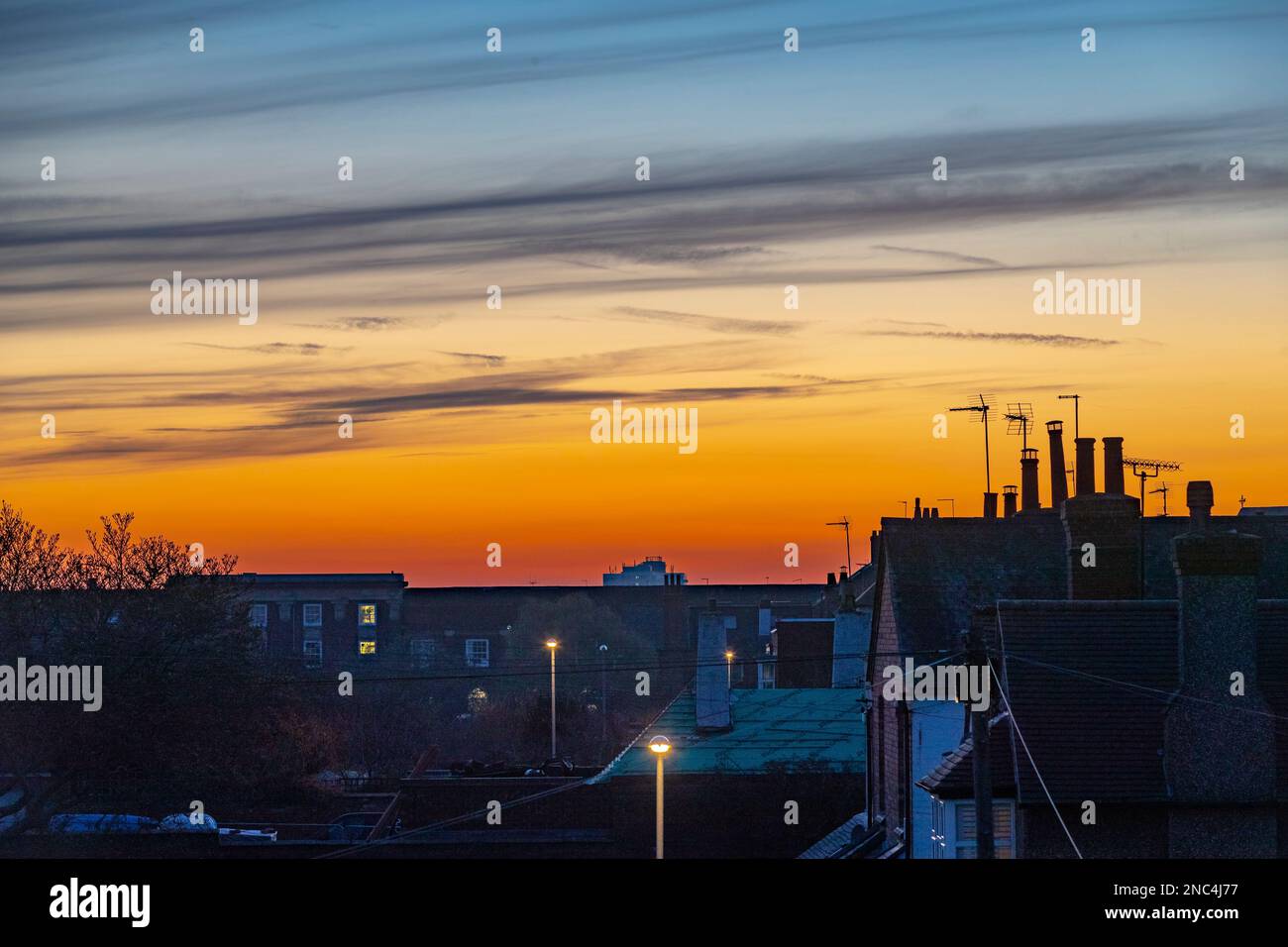 Northampton, Großbritannien. Wetter, 14. Februar 2023. Ein schöner Sonnenuntergang über den Dächern nach einem sehr nebligen Start in den Tag. Kredit: Keith J. Smith./Alamy Live News Stockfoto