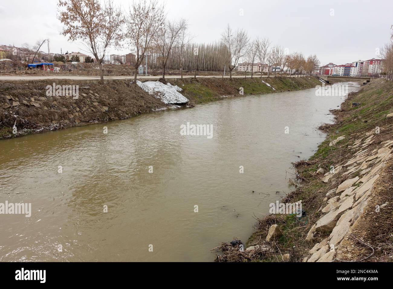 Ein Fluss mit trüben Gewässern, ein Fluss, der durch eine Siedlung fließt, Stockfoto