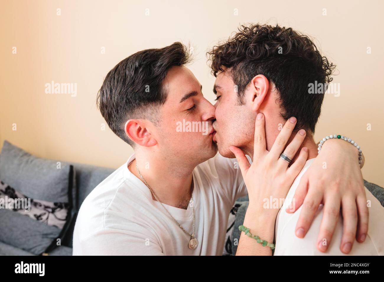 Ein junges schwules Paar im Pyjama, das sich romantisch auf den Mund küsst. Valentinstag Stockfoto