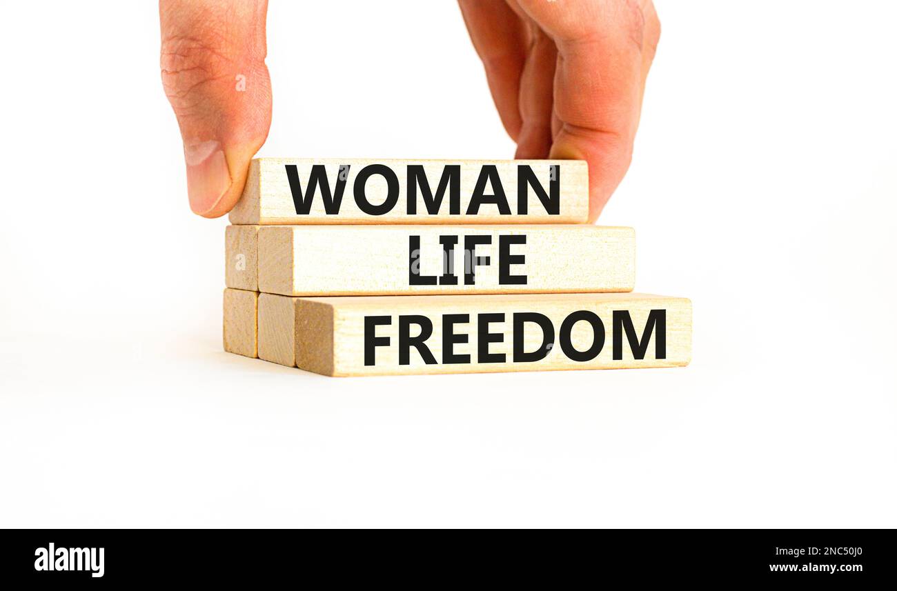 Das Symbol für die Freiheit des Lebens der Frau. Konzeptwörter Woman Life Freedom auf Holzblöcken auf einem wunderschönen weißen Tischhintergrund. Geschäftsmannshand. iss für soziale Medien Stockfoto