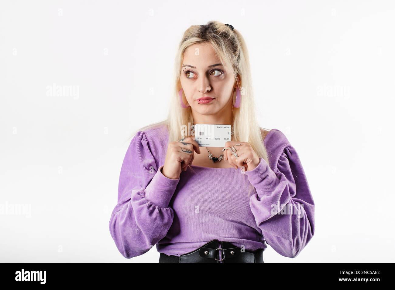 Porträt einer fröhlichen Frau mit Bluse, die isoliert auf weißem Hintergrund steht und eine Kreditkarte hält, blickt auf den leeren Kopierraum und die Tagträume. D Stockfoto