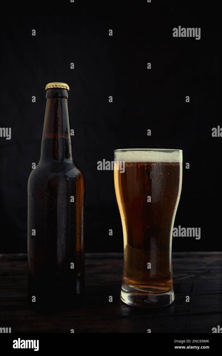 Eine Flasche und ein Glas Bier auf dunklem Hintergrund. Stockfoto