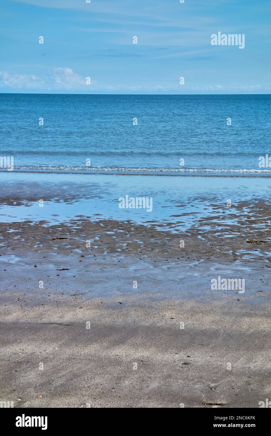 Ein Sandstrand mit blauem Meer und blauem Himmel. Stockfoto