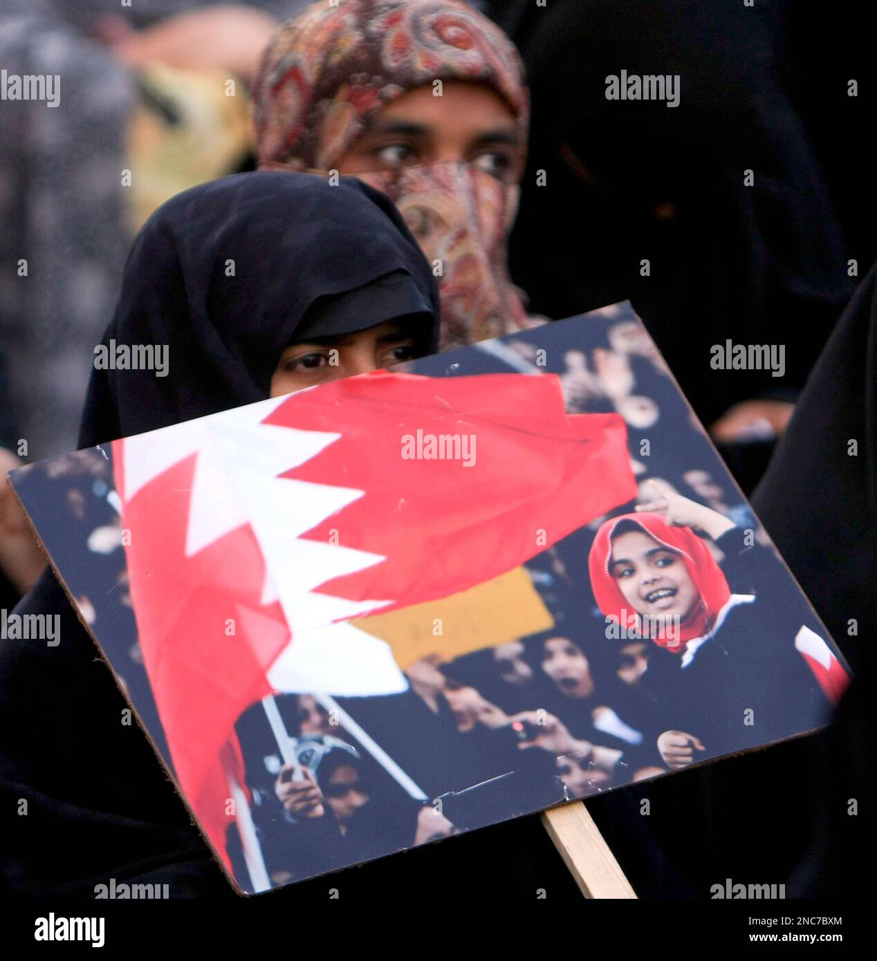 A Pakistani Shiite Muslim woman holds up a placard bearing a photograph from Bahrain, during a rally in support of anti-government protesters in Libya, Tunisia, Bahrain and Yemen, in Karachi, Pakistan, Sunday, Feb. 27, 2011. (AP Photo/Fareed Khan) Stockfoto