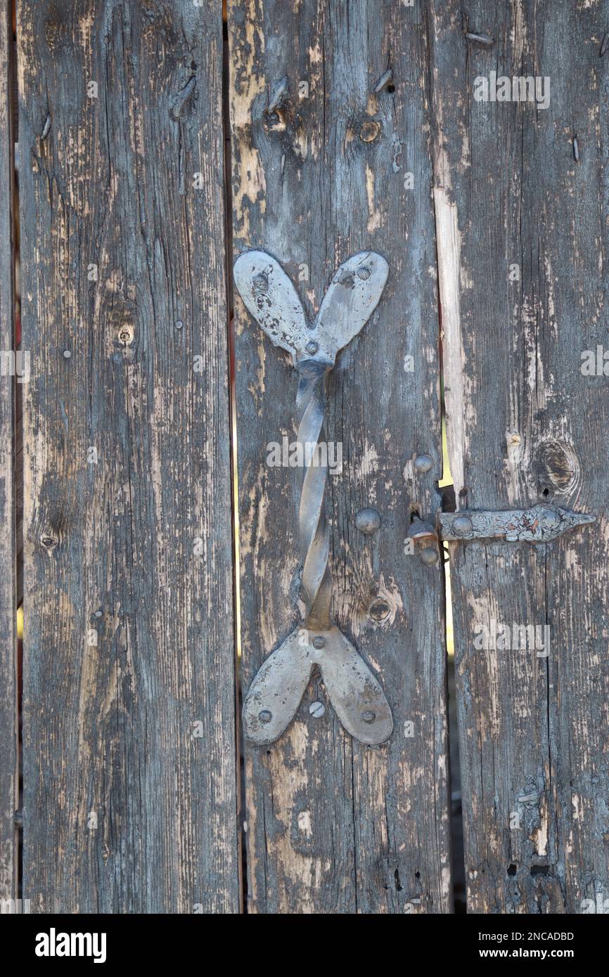 Graue pastellfarbene Holztür mit dekorativen hart-förmigen vertikalen Streifen mit Metallgriff in Silber, Türen öffnen und schließen Stockfoto
