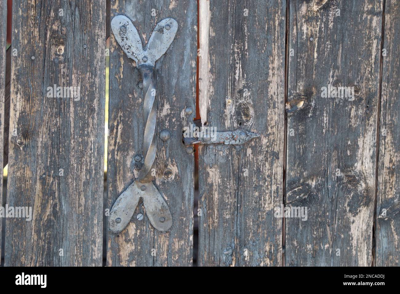 Graue pastellfarbene Holztür mit dekorativen hart-förmigen silbernen Metallgriffen vertikale Streifen zum horizontalen Öffnen und Schließen der Türen Stockfoto