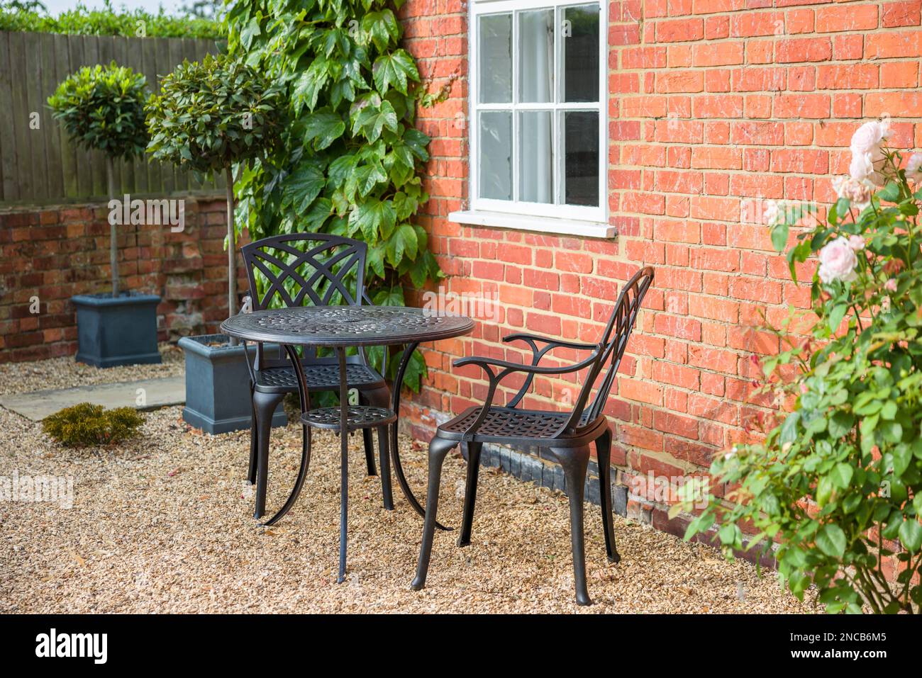 Gartengestaltung mit Bistrotisch und Stühlen auf Kies im traditionellen britischen Garten Stockfoto