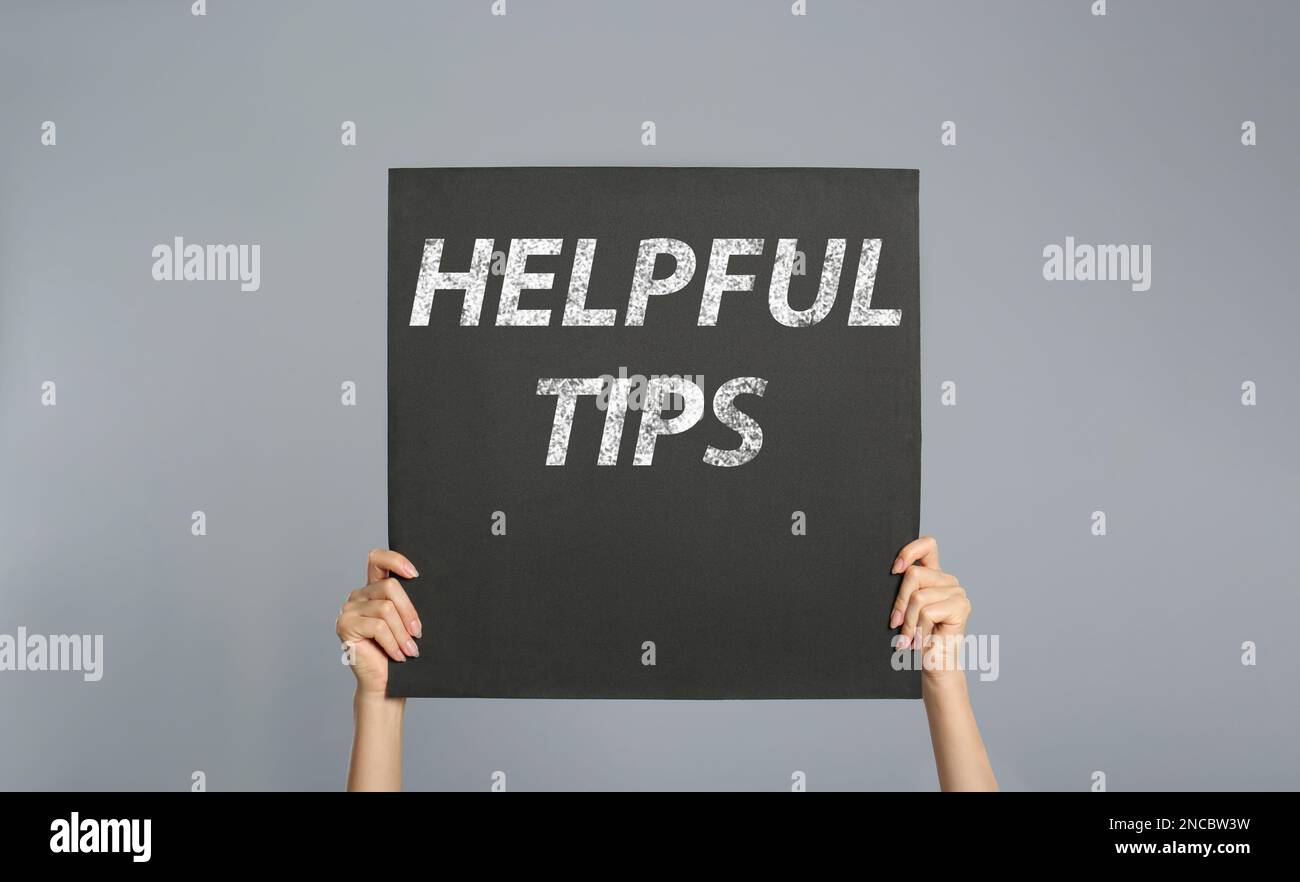 Frau mit Poster mit Satz hilfreiche Tipps auf grauem Hintergrund, Nahaufnahme Stockfoto