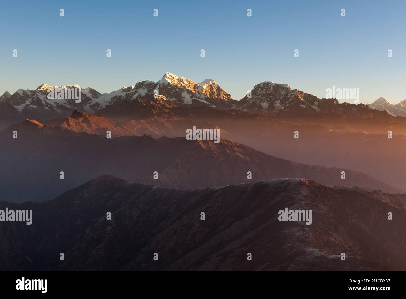 Berglandschaft bei Sonnenaufgang im Himalaya, Nepal. Wolken schweben über Berglandschaft mit hohen Gipfeln am Horizont. Stockfoto
