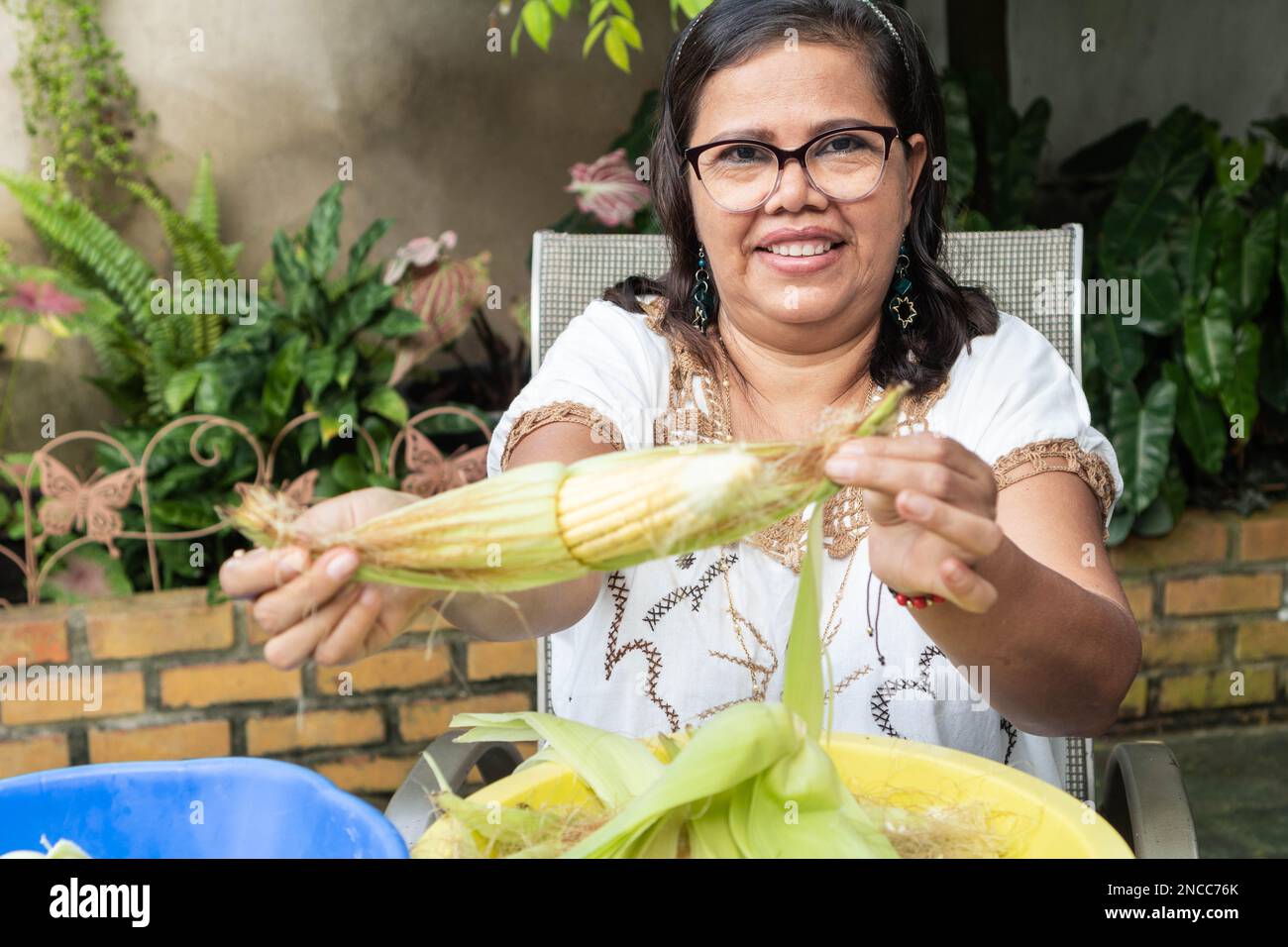 Eine einheimische mexikanische Frau, die Mais schält, um Teig für Tortillas, ein typisches mexikanisches Essen, herzustellen. Stockfoto