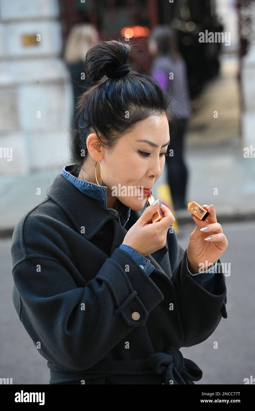14. Februar 2023 London, Großbritannien. Eine Asiatin, die Lippenstift in Whitehall, London, Großbritannien, legt. Stockfoto