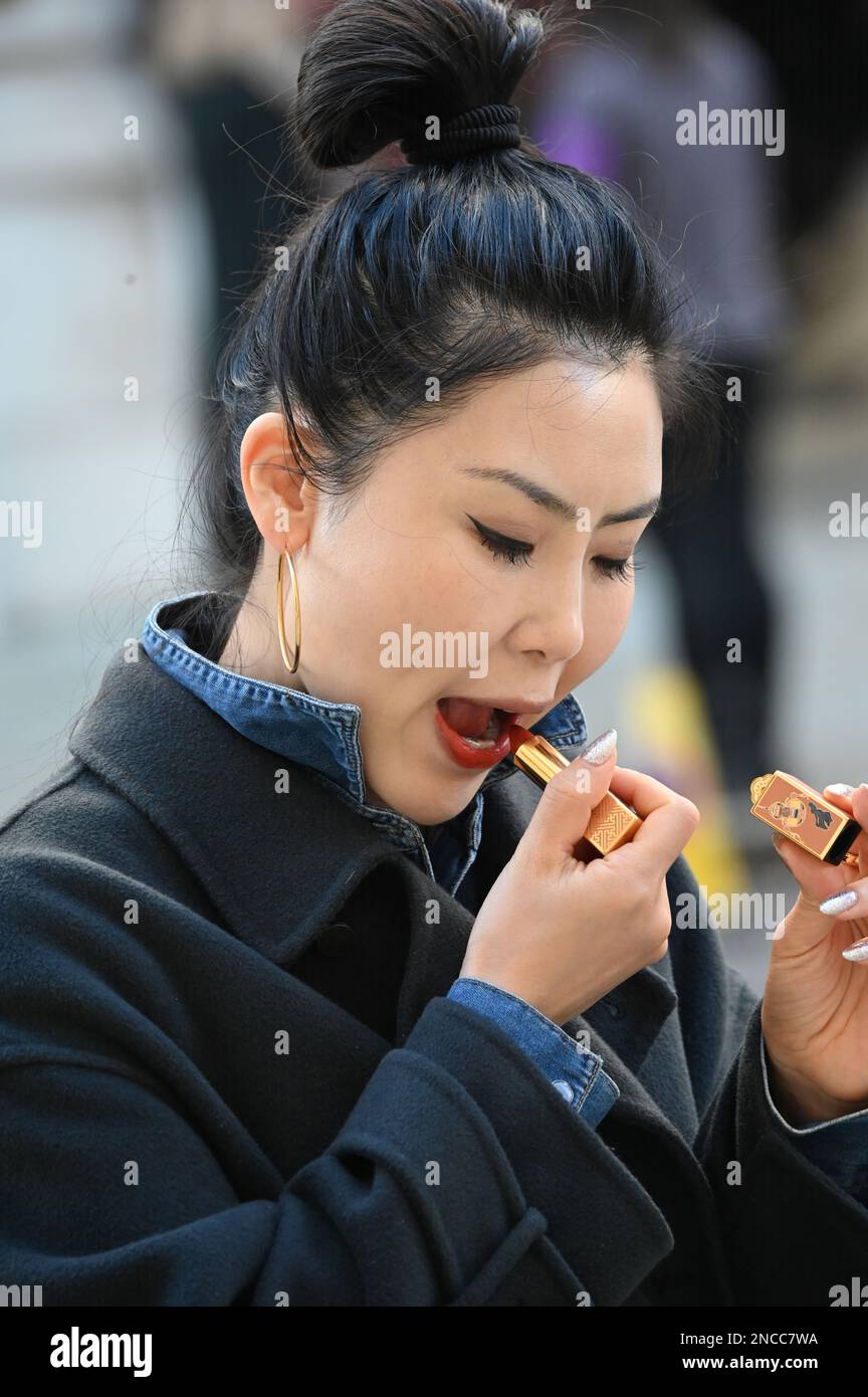 14. Februar 2023 London, Großbritannien. Eine Asiatin, die Lippenstift in Whitehall, London, Großbritannien, legt. Stockfoto