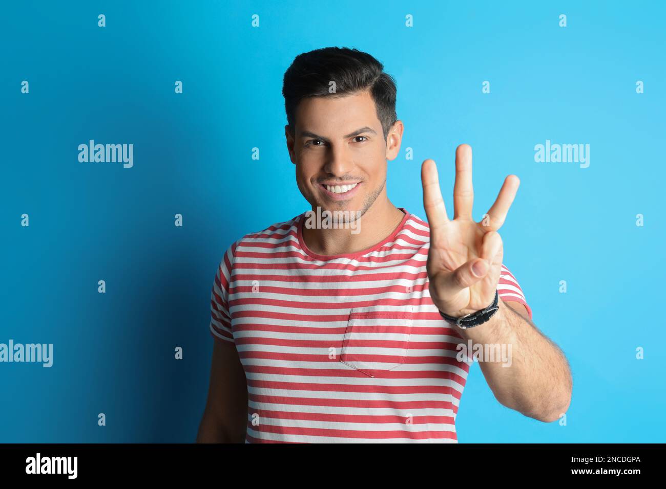 Ein Mann zeigt Nummer drei mit seiner Hand auf hellblauem Hintergrund Stockfoto