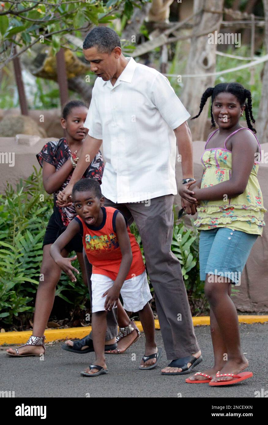 President Barack Obama trips over Xavier Nesbitt as he walks with his daughter Sasha Obama, left, and another of the Nesbitt children through Honolulu Zoo in Honolulu, Monday, Jan. 3, 2011. (AP Photo/Carolyn Kaster) Stockfoto