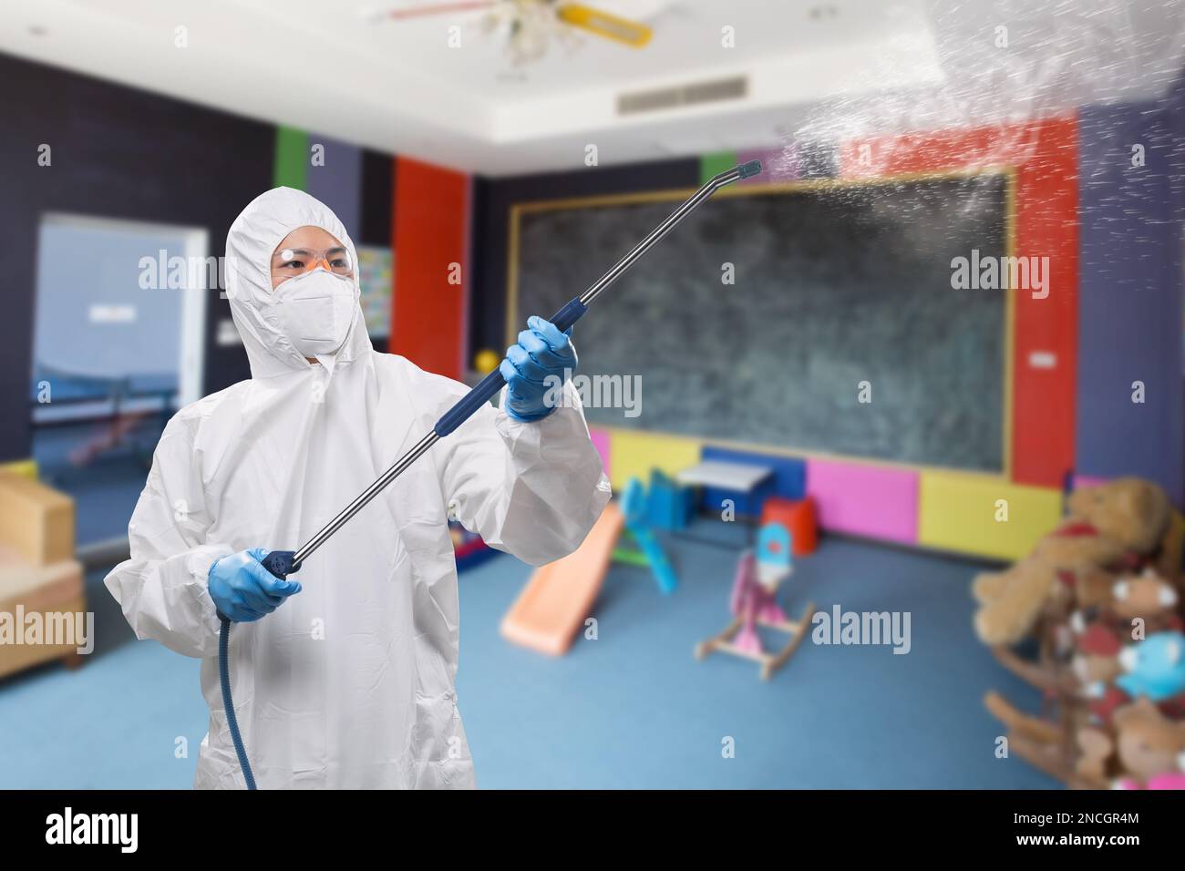 Arbeiter trägt medizinischen Schutzanzug oder weißen Overall Anzug mit Spray desinfizieren Stockfoto