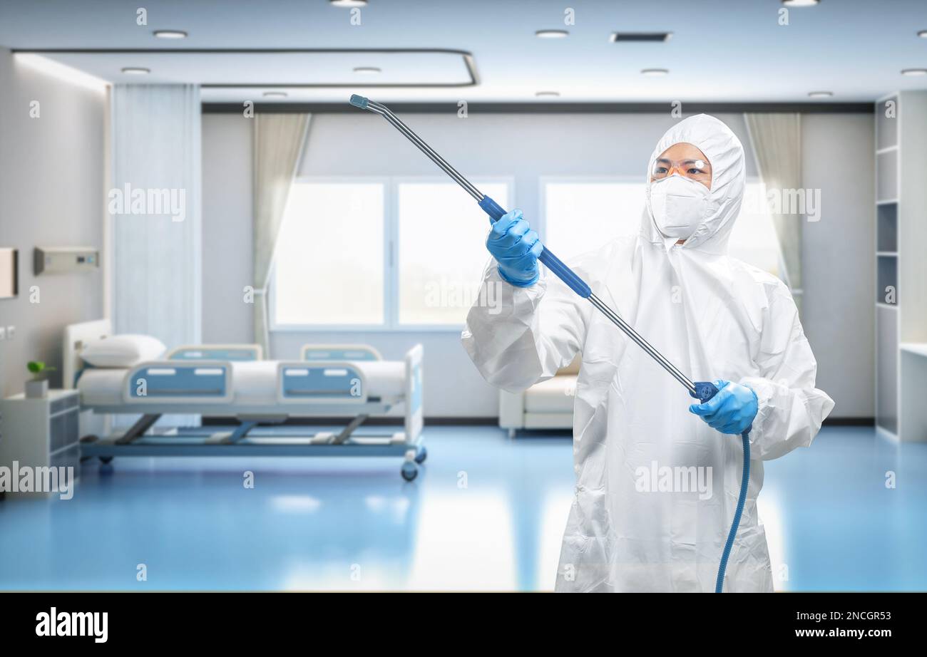 Arbeiter trägt medizinischen Schutzanzug oder weißen Overall Anzug desinfizieren mit Spray im Krankenhauszimmer Stockfoto