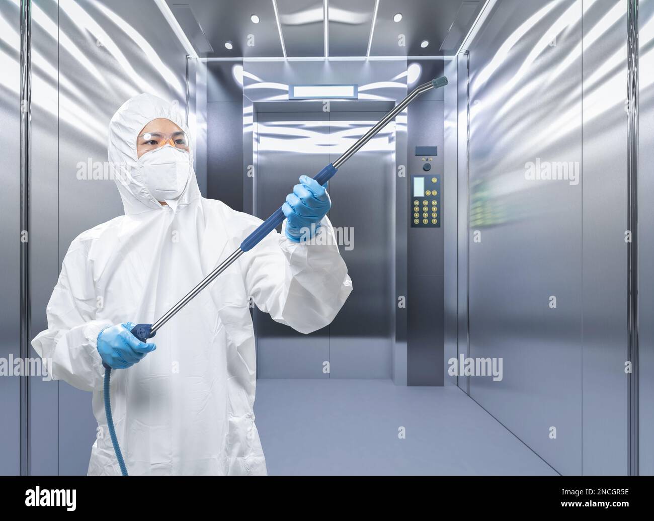 Arbeiter trägt medizinischen Schutzanzug oder weißen Overall Anzug desinfizieren mit Spray im Aufzug Stockfoto