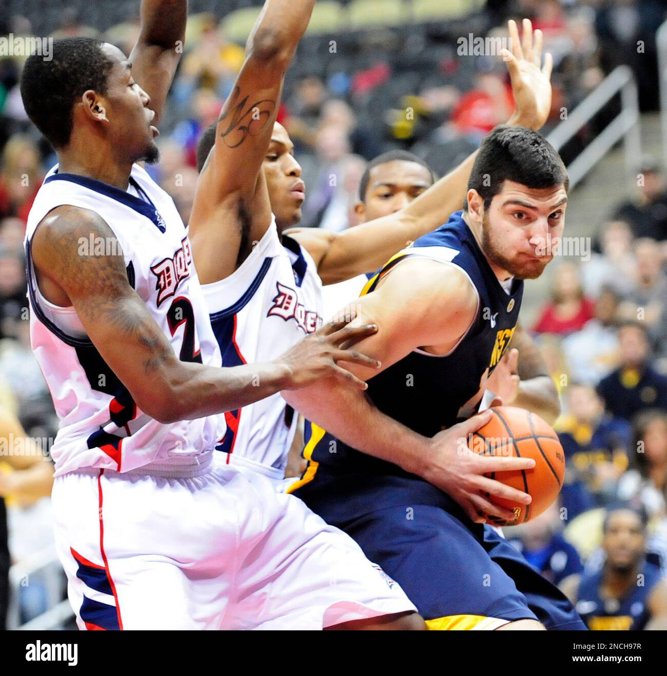 Duquesne defenders trap West Virginia's Deniz Kilicli, right, under the basket during the second half of an NCAA college basketball game in Pittsburgh, Sunday, Dec. 12, 2010. West Virginia won 64-61. (AP Photo/John Heller) Stockfoto