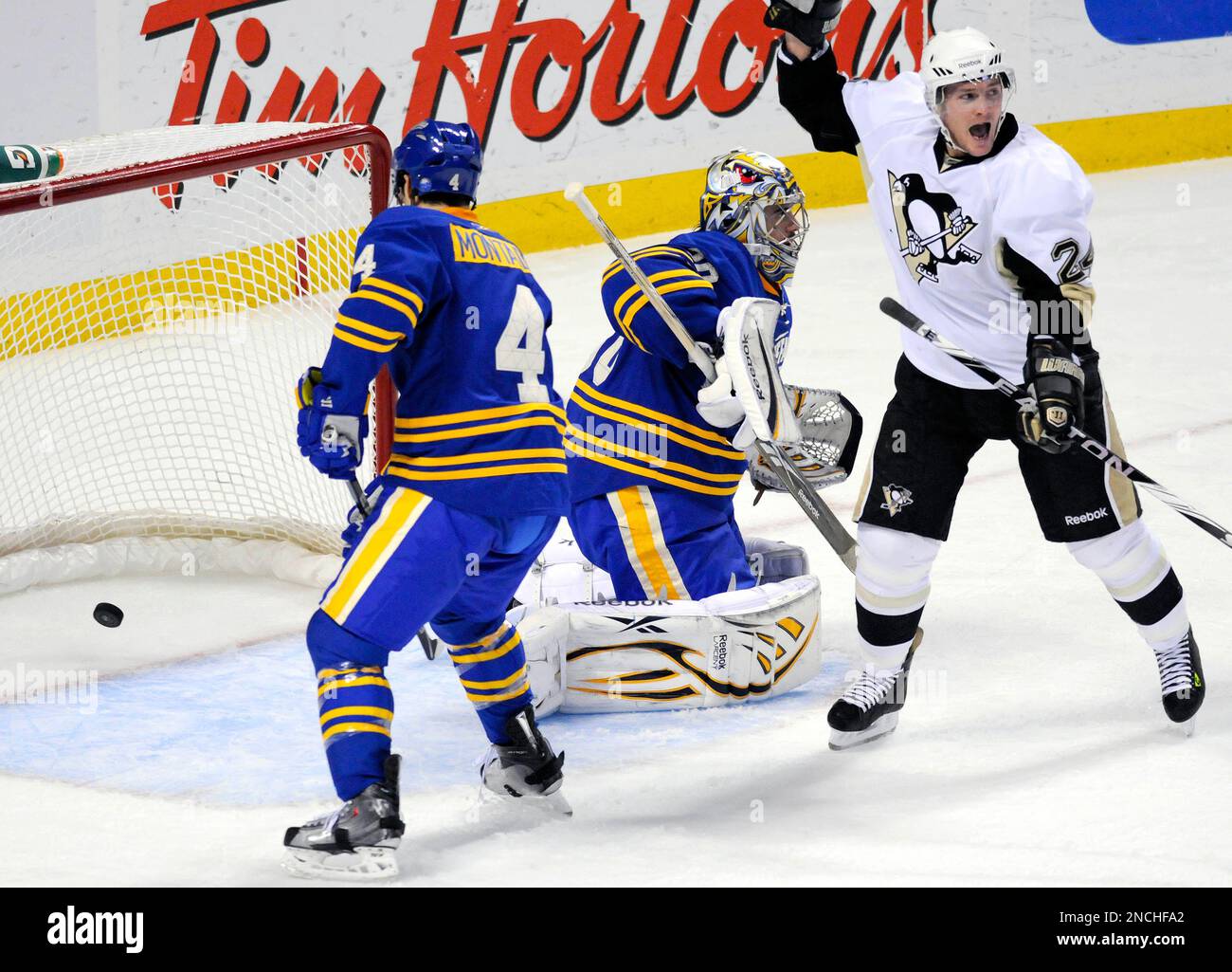 Pittsburgh Penguins winger Matt Cooke, right, celebrates Penguins Arron Asham's goal against Buffalo Sabres goalie Ryan Miller, center, as Sabres defenseman Steve Montador skates towards the net during the first period of an NHL hockey game, Saturday, Dec. 11, 2010, in Buffalo, N.Y. (AP Photo/Don Heupel) Stockfoto