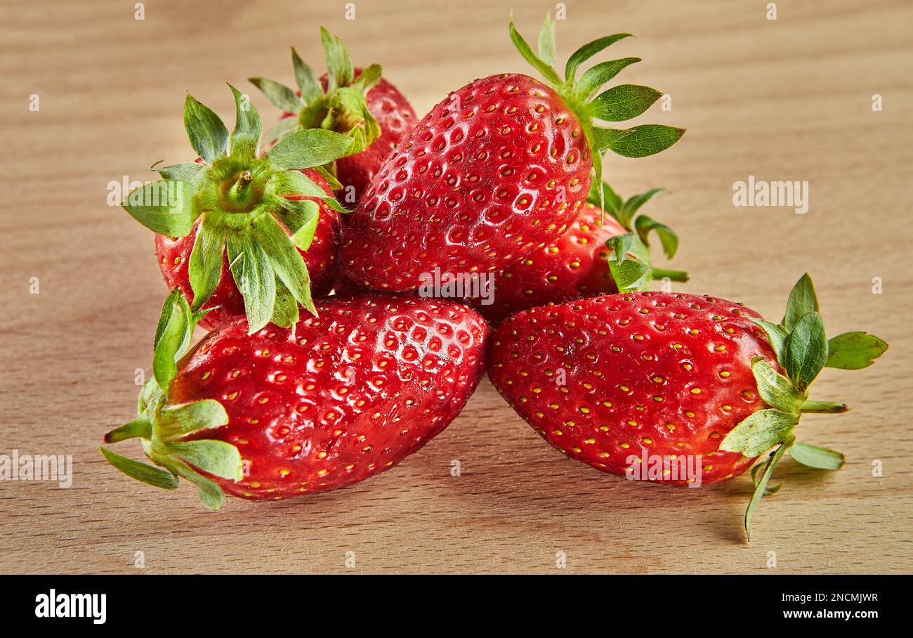 Frisch ausgewählte Erdbeeren, gestapelt auf einer Rutsche auf Holzhintergrund Stockfoto