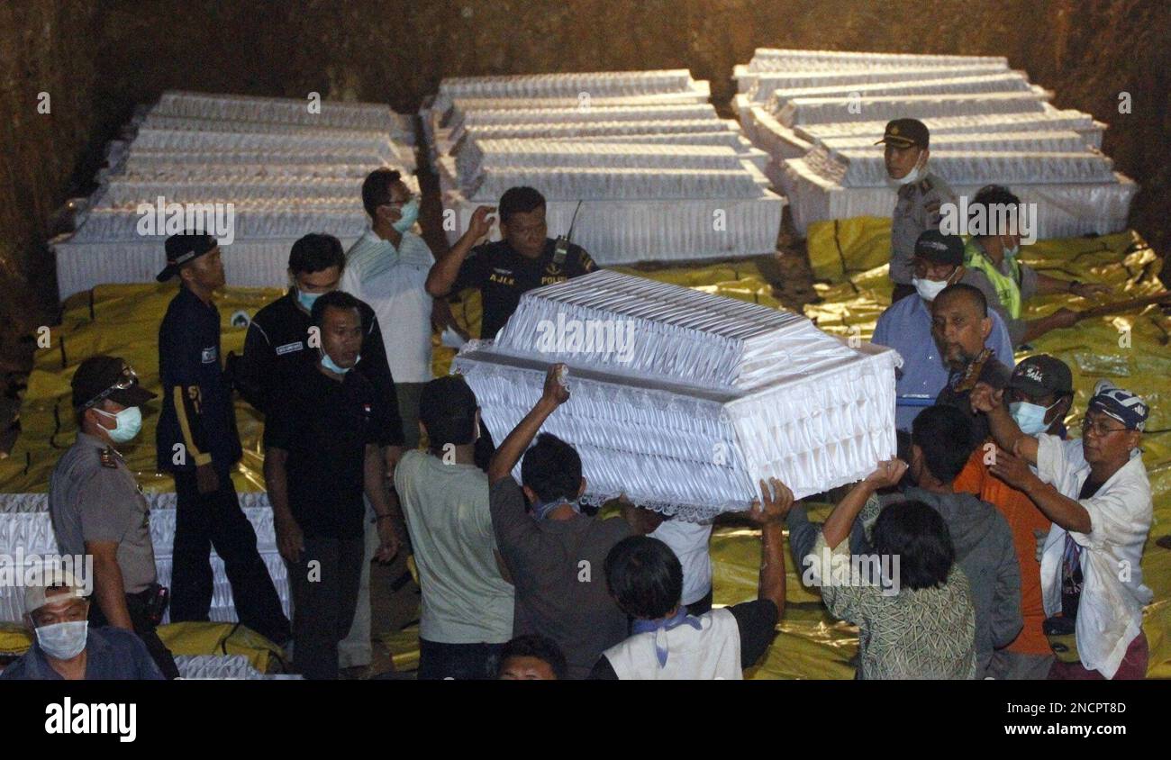 Indonesian volunteers and police carry coffin at the grave for mass ...