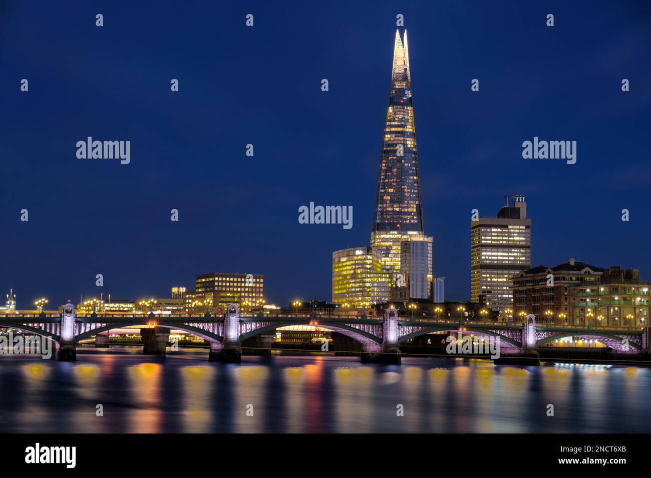 Nachtaufnahme der Londoner Skyline mit Shard und Boot auf der Themse Stockfoto