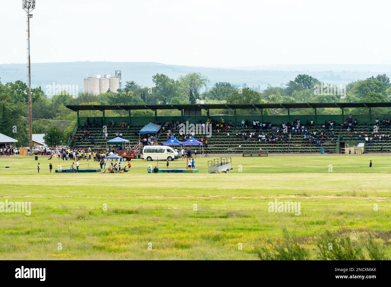Schulsporttag in einem Sportstadion in einer ländlichen Stadt in Südafrika mit Zuschauern auf der Tribüne und Kindern auf den Feldern Stockfoto