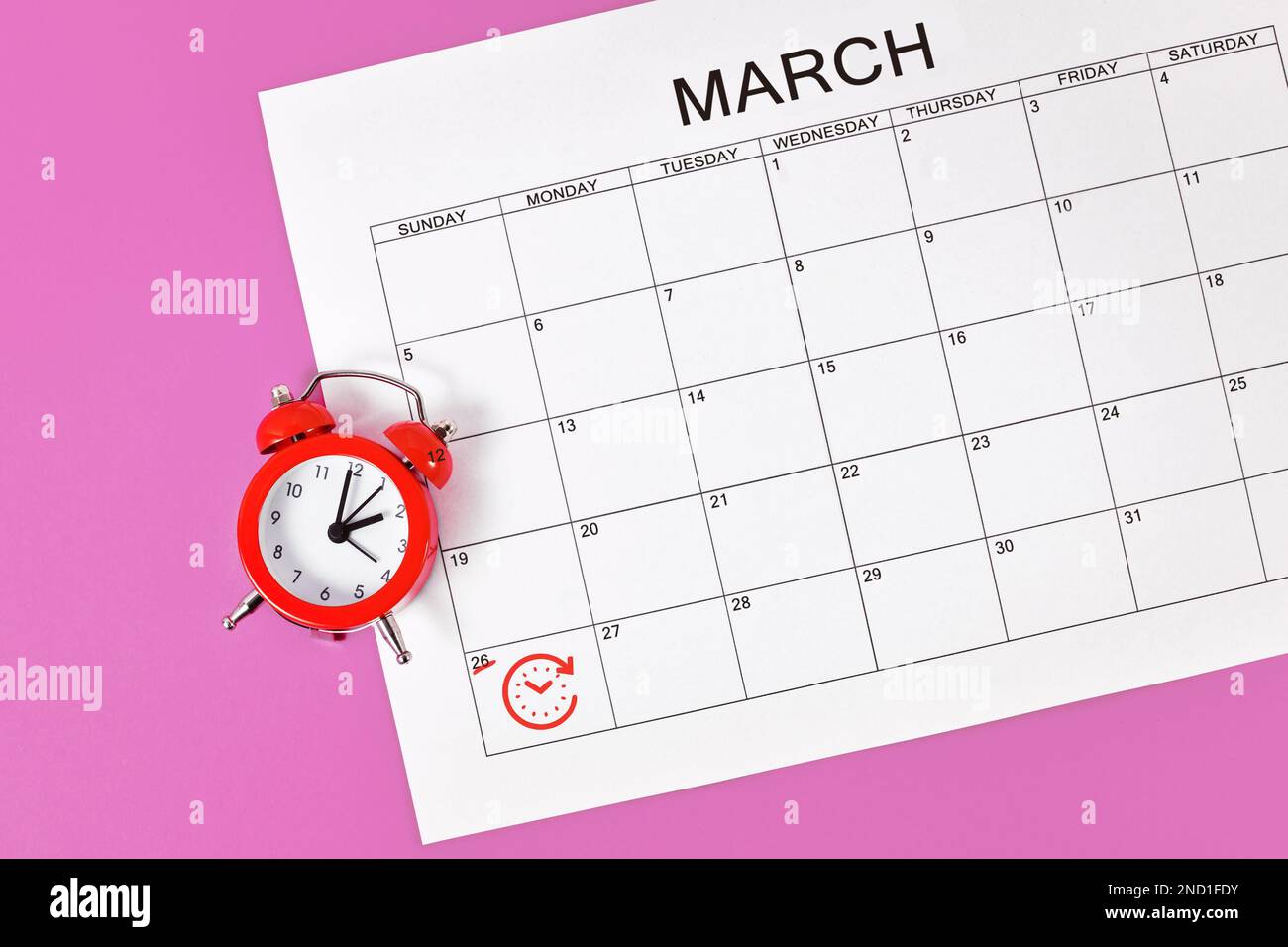 Zeitänderungskonzept für mitteleuropäische Sommerzeit am 27. März mit rotem Wecker und Kalenderblatt Stockfoto