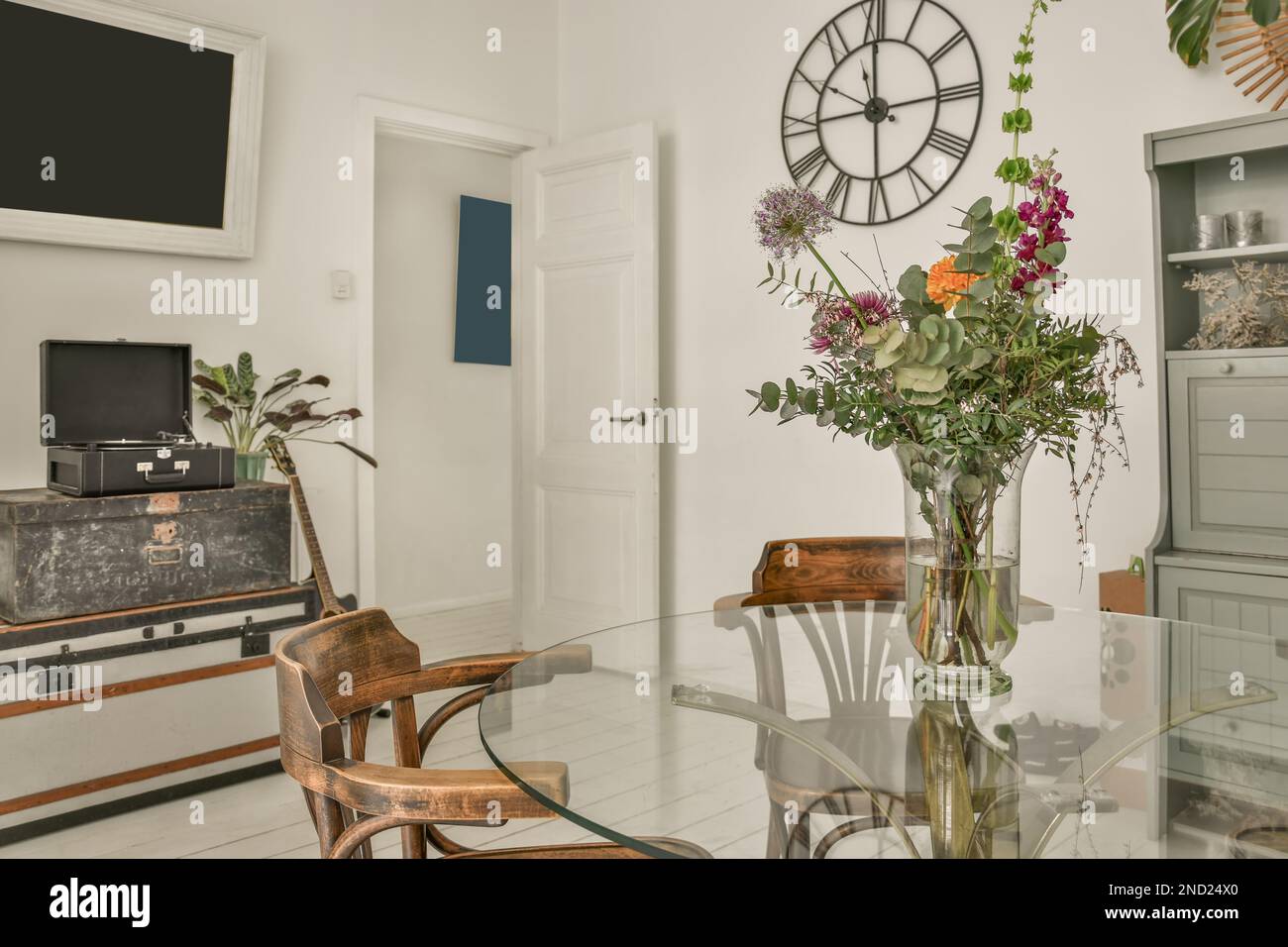 Innendesign des Esszimmers mit Glastisch, dekoriert mit Blumen in Vase  neben Regalen und Fernseher Stockfotografie - Alamy