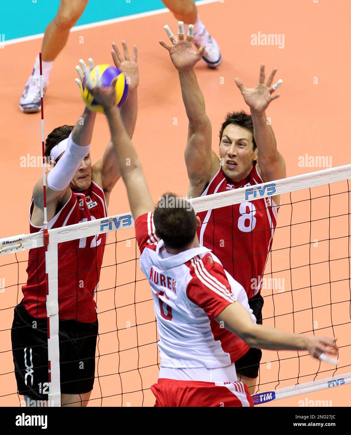 Poland's Bartosz Kurek, back to camera, goes for the ball with Canada's Gavin Schmitt, left, and Adam Simac during a first round match between Canada and Poland at the Men Volleyball World Championships, in Trieste, Italy, Saturday, Sept. 25, 2010. (AP Photo/Paolo Giovannini) Stockfoto