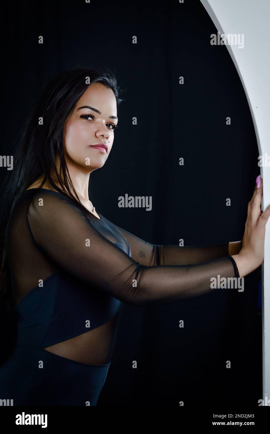 Porträt einer wunderschönen jungen brasilianischen Frau, die sich mit intensivem Blick an eine Wand lehnt Stockfoto