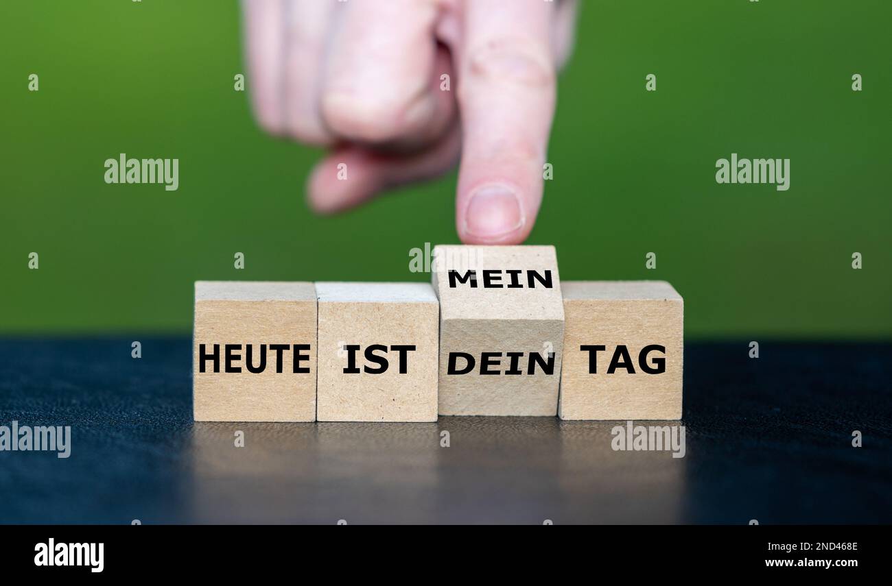 Die Hand würfelt und ändert den deutschen Ausdruck „heute ist dein Tag“ (heute ist dein Tag) in „heute ist mein Tag“ (heute ist mein Tag). Stockfoto