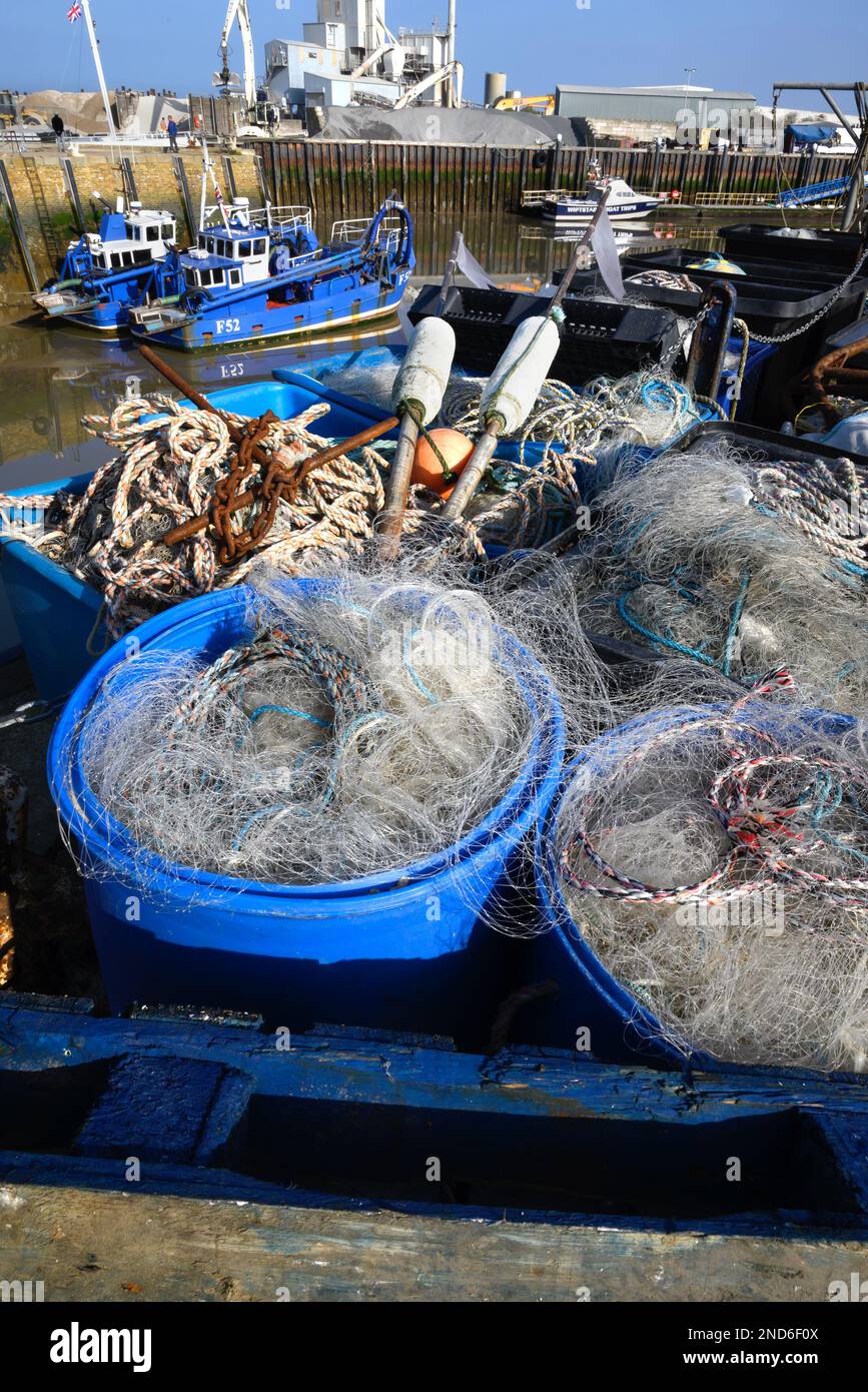 Whitstable, Kent, England, Großbritannien. Fischernetze, Seile und Anker in Körben an der Hafenmauer Stockfoto