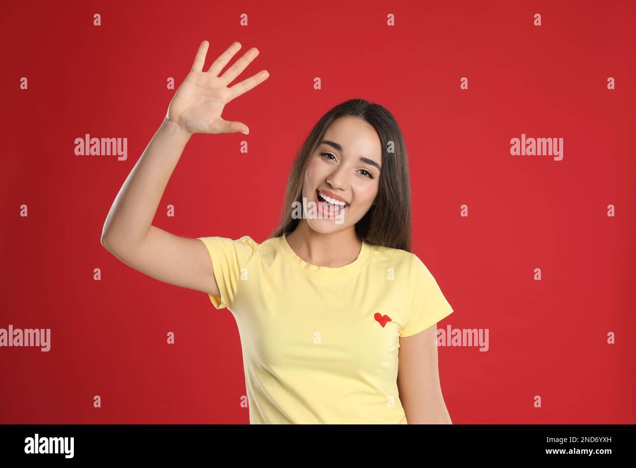 Eine Frau in einem gelben T-Shirt, die Nummer fünf mit ihrer Hand auf rotem Hintergrund zeigt Stockfoto