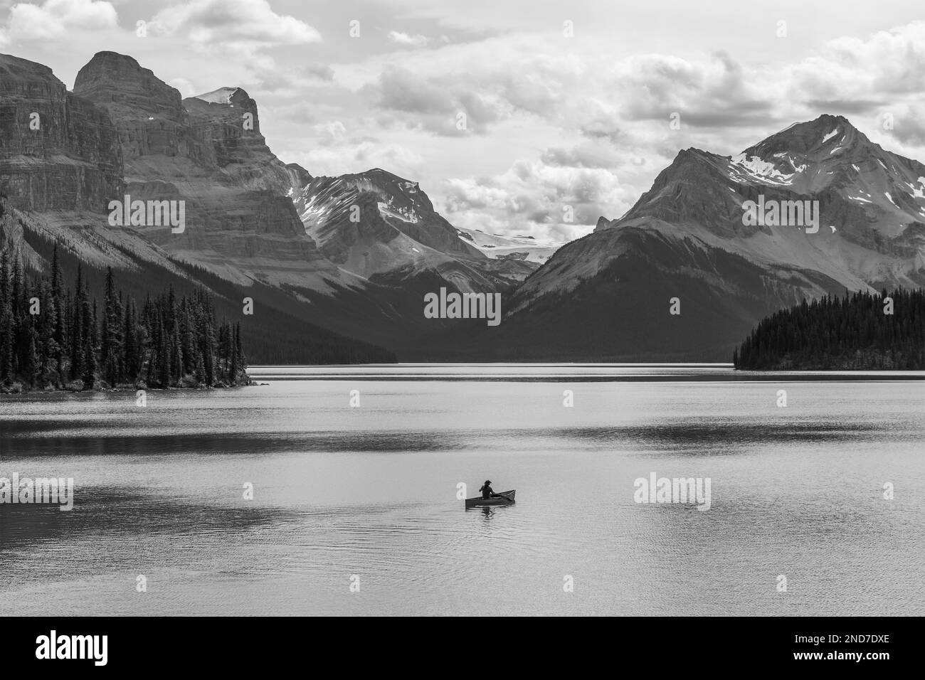 Ein einsamer Abenteurer auf einer Kanufahrt in Schwarz und Weiß auf dem Maligne Lake, den kanadischen Rockies, dem Jasper-Nationalpark, Alberta, Kanada. Stockfoto