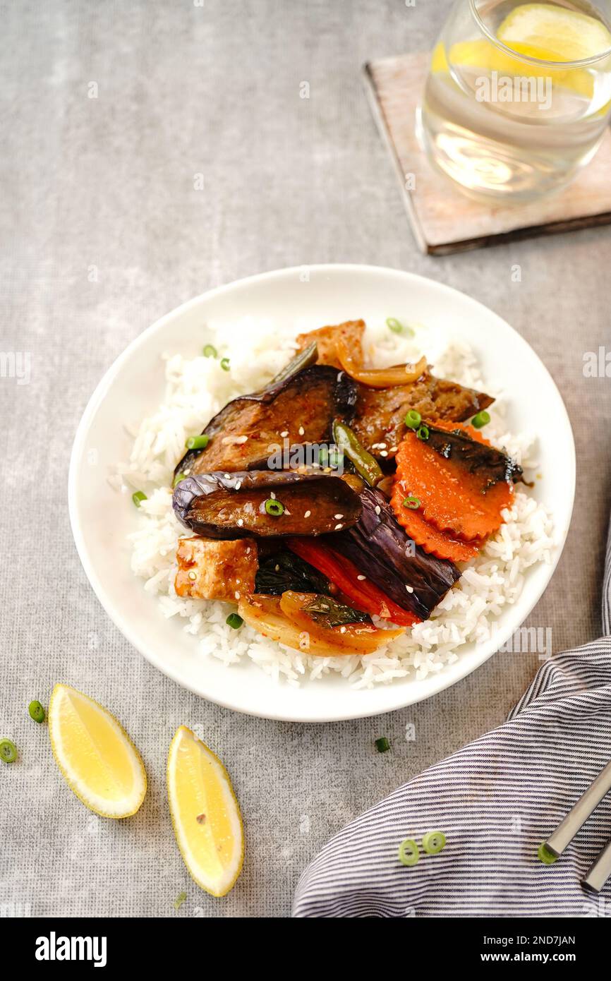 Gebratene thailändische Aubergine mit Gemüse in süßer Sauce, serviert mit Jasminreis Stockfoto