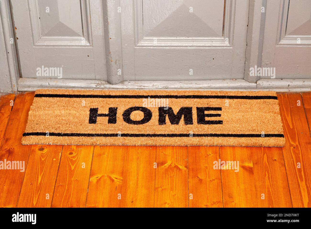 Nahaufnahme einer Fußmatte mit der Aufschrift „Home“ vor einer Wohnungstür. Stockfoto