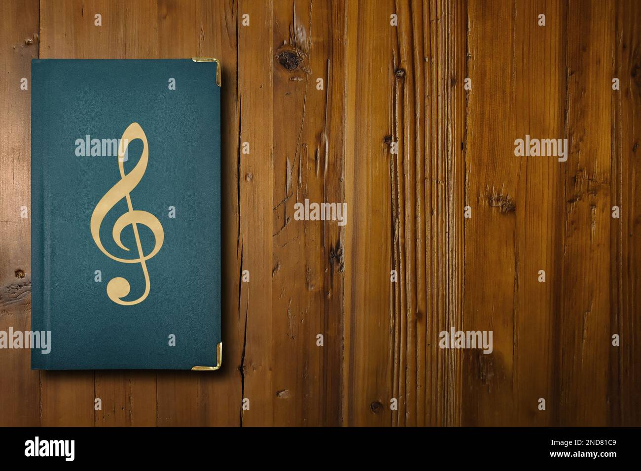 Nahaufnahme eines grünen Buches mit einer vergoldeten Musiknote in der Mitte. Stockfoto