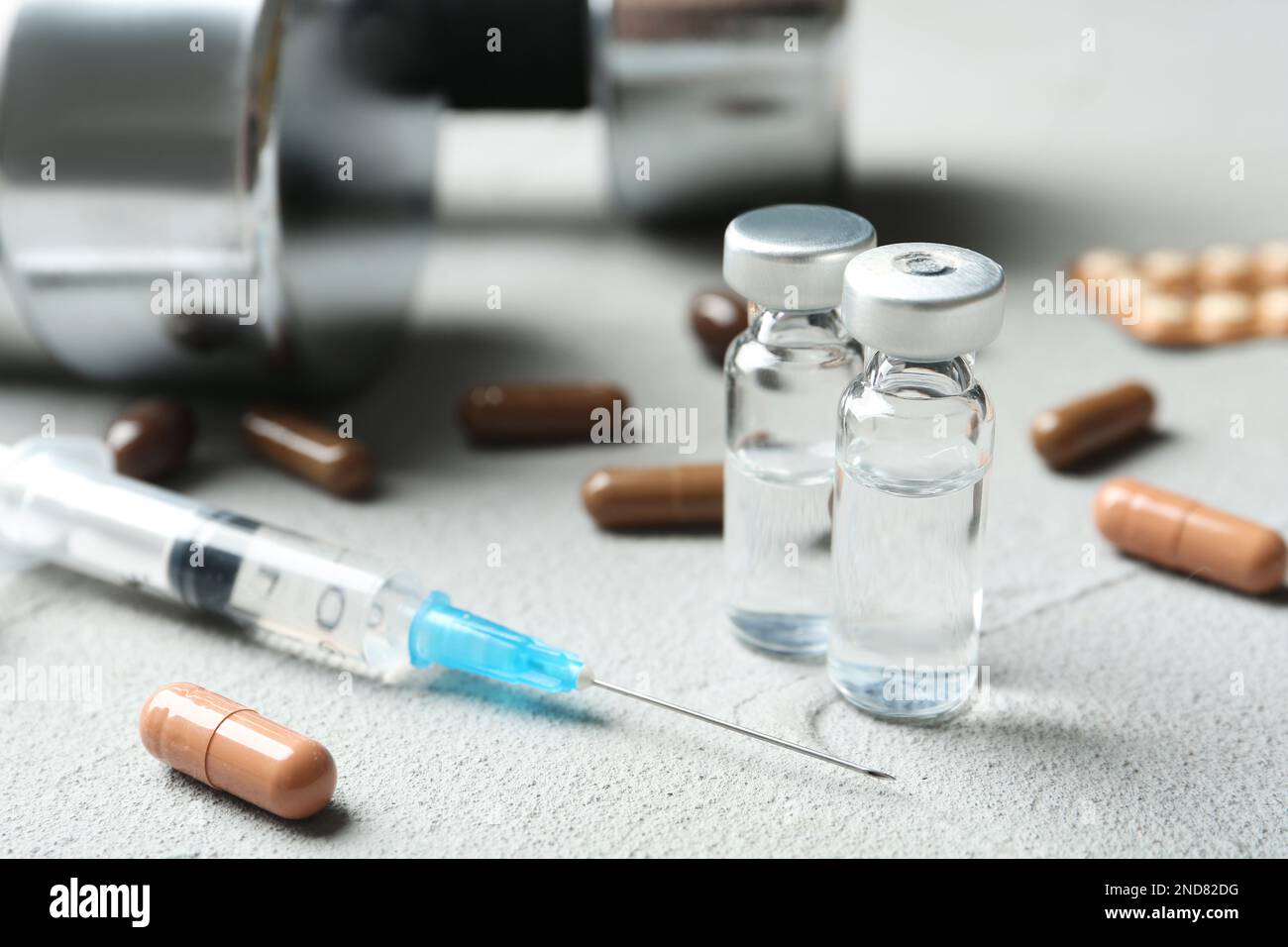 Verschiedene Medikamente und Kurzhanteln auf hellgrauem Tisch. Dopingkontrolle Stockfoto