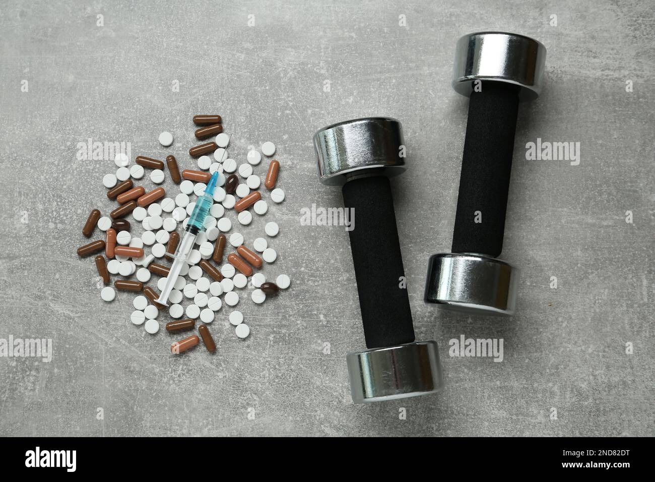 Verschiedene Drogen und Sportgeräte auf grauem Tisch, flach liegend. Dopingkontrolle Stockfoto